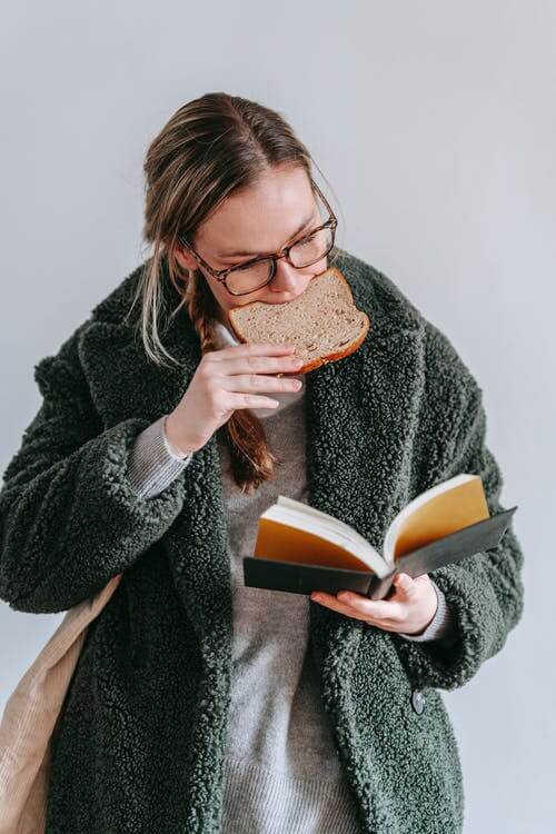 Woman reading a book and eating gluten aka break. Why avoid gluten?
