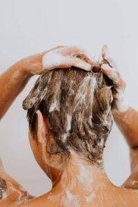 White woman with blonde hair washing her hair due to seborrheic dermatitis. Best seborrheic dermatitis treatment,