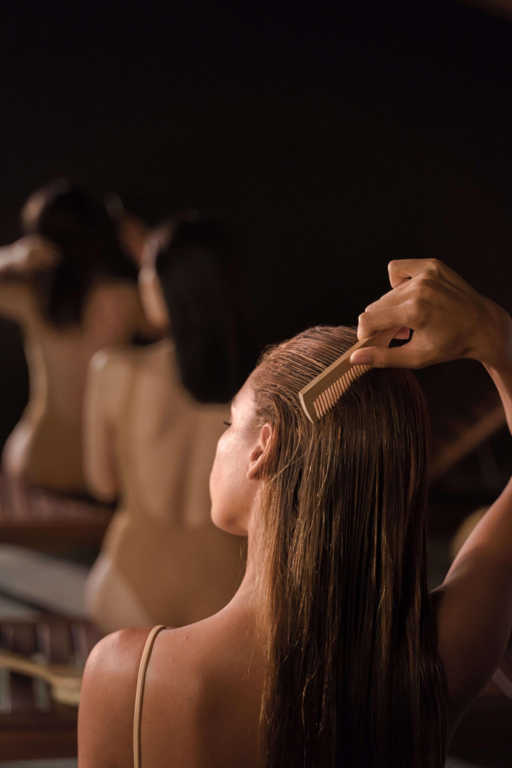 White woman brushing her long straight hair. Does seborrheic dermatitis cause hair loss?