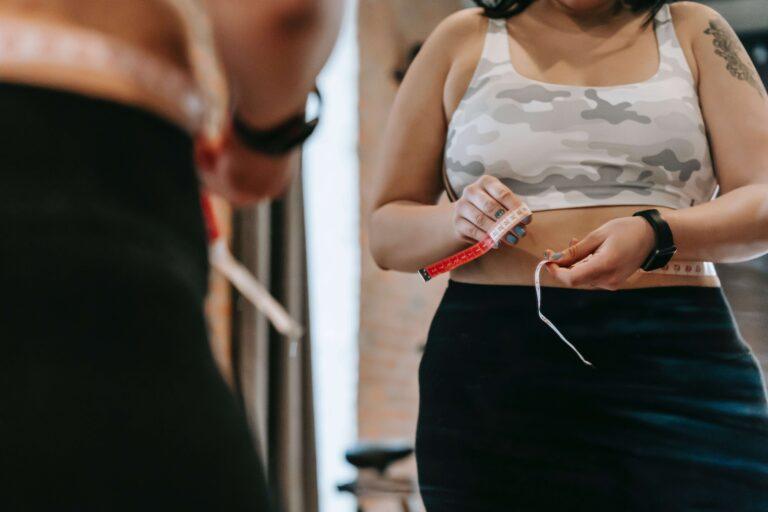 White Woman measuring waistline with measuring tape. Gut health