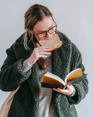 Woman reading a book and eating gluten aka break. Why avoid gluten?