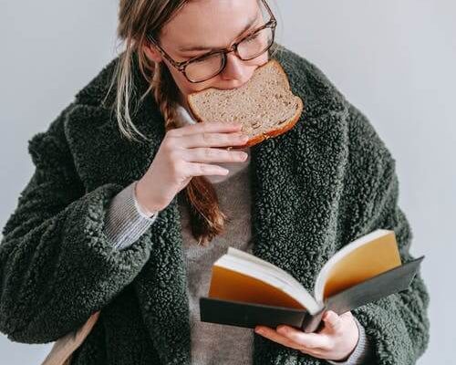 Woman reading a book and eating gluten aka break. Why avoid gluten?